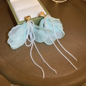 Blue fabric flower tassel drop earrings with white beads and gold heart studs on green box