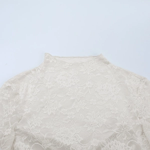 Gros plan sur le motif dentelle florale et le col montant d'un haut blanc sexy