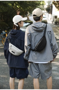 Outdoor street view of the black and beige crossbody chest bags with adjustable straps