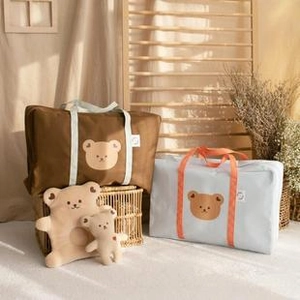 Detail of embroidered bear quilted diaper bag and stroller storage bag with accessories