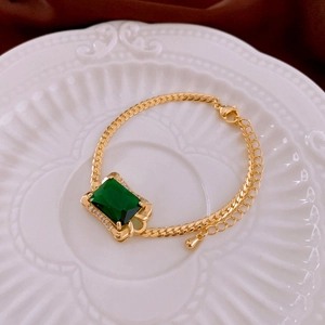 Close-up of a vintage gold chain bracelet featuring a green emerald-cut zircon stone