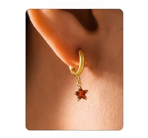 Close-up of golden stainless steel hoop earring with a red star glass crystal pendant