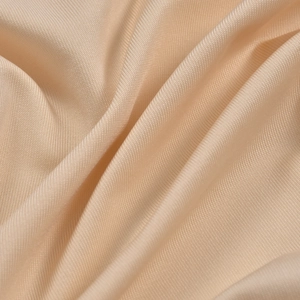 Vue macro du tissu tricoté champagne doré haute densité avec une texture de soie douce