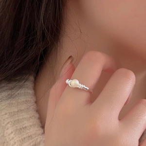 Macro shot of minimalist silver pearl ring showing detailed wire wrap setting on finger