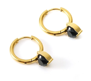 Close-up of gold hoop earrings with black zircon heart pendants on white background