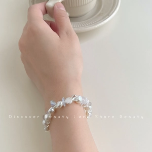Close-up of elegant baroque natural pearl bracelet worn while holding a porcelain cup