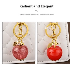 Detailed view of red apple keychains with glitter and gold leaves on white bag