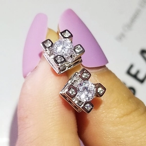 Close-up of square zircon stud earrings with silver finish held between fingers