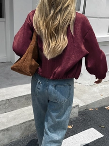 Street style view of a woman in a wine red cropped jacket and blue straight jeans