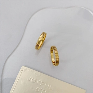 Detail of two gold plated stackable rings with vertical ribbed texture on acrylic plate