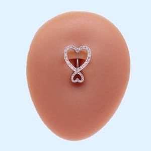Close-up of a silver heart-shaped navel ring with crystals on a silicone body model