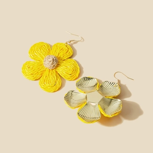 Handwoven yellow raffia flower earrings with gold metal hooks on a beige background
