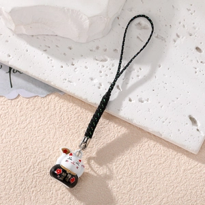 Close-up of Maneki Neko charm with Lucky Fortune kanji on textured stone background