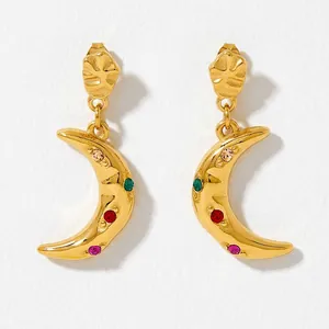 Détail de boucles d'oreilles lune dorées serties de zircons colorés de style bohème