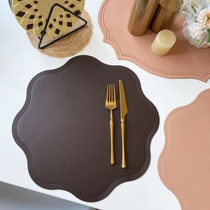 Faux leather placemat with scalloped edges and textured surface for dining table decor
