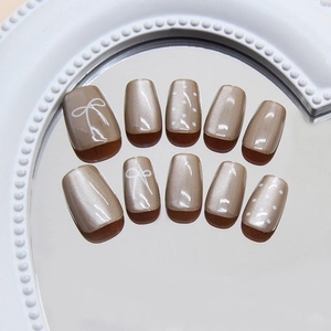 Champagne bow and polka dot press-on nails with shimmering cat-eye pearl finish