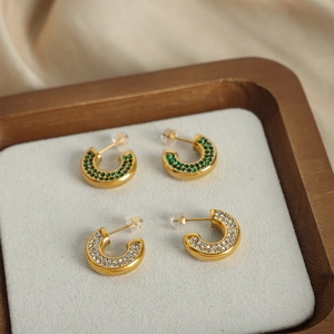 Gold-plated C-shaped earrings with micro-set green and white crystals on velvet