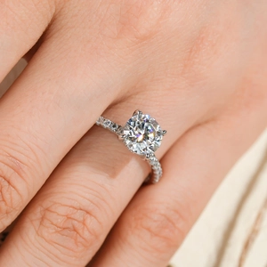 Classic four-prong 2ct moissanite ring with pavé-set side stones on a silver-tone band