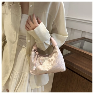 Detailed close-up of a pink silk handbag with vintage floral embroidery and pearl accents