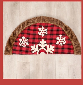 Detailed close-up of red and black plaid Christmas tree skirt with white snowflake appliques