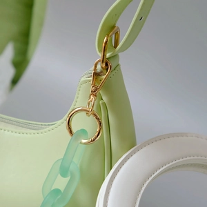 Detail of lime green bag with gold metal ring clasp and frosted green chain strap