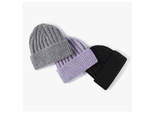 Detailed texture of thick knit beanies in grey, purple, and black with folded cuffs