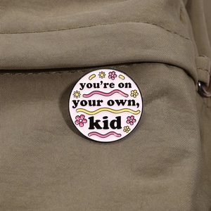Pink enamel pin featuring 'you're on your own, kid' lyrics on khaki canvas bag
