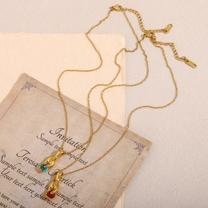 Détail de pendentifs en main avec pierres rouges et bleues et poinçon K18 doré
