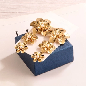 Elegant gold layered flower earrings with pearl centers on a navy jewelry box display