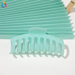 Detail of a large mint green matte hair claw clip on a minimalist aesthetic background