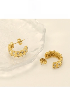 Detail view of gold C-shape earrings featuring 18K plating and round cut zircons