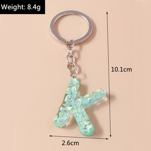 Detail view of a green glitter letter K keychain with dimensions and weight specs