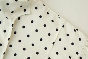 Detail shot of stand collar and polka dot print on white long sleeve jacket