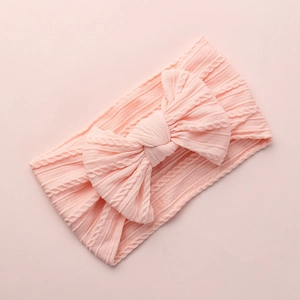 Detail of baby ribbed knit texture of a soft pink infant headband with a large decorative bow