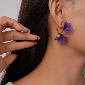Detail of purple fabric floral C-shape earrings with polished gold-tone metal accents