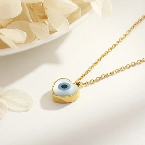 Macro detail of a 18k gold plated evil eye heart pendant necklace with dried flower petals