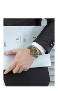 Close-up of a men's ultra-thin watch with green leather strap and silver case on wrist