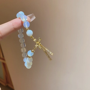 Close-up of cat eye stone beads with a golden zircon bow charm and long tassels
