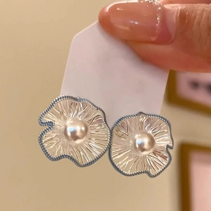 Detail of silver hollow flower earrings with white pearls and textured petals