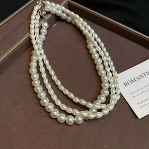 Macro detail of multi-layered pearl necklace with silver clasp on leather tray
