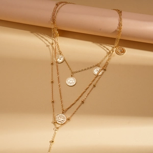 Three-layer gold metal necklace with Capricorn coin pendant and tassel on beige podium