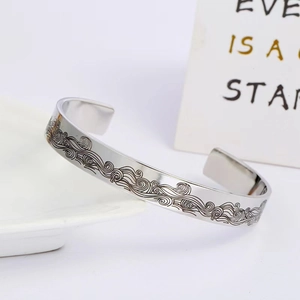 Macro detail of silver C-shaped cuff bracelet with polished wave pattern engraving