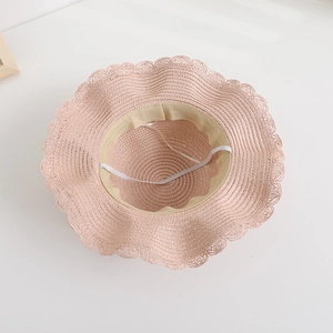 Detail of pink woven straw hat showing wavy brim, inner sweatband and elastic chin strap