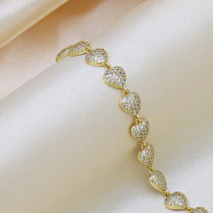 Elegant gold-plated heart bracelet with zircon pavé on luxurious beige silk background