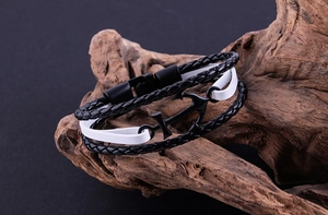 Detail view of woven leather layers and black anchor charm on vintage wood base