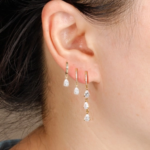 Close-up of gold pear-cut zircon earrings set on ear, featuring sparkling drop pendants