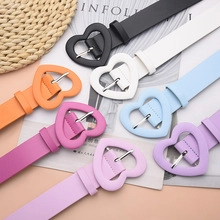 Flat lay of colorful women's belts with matching matte heart-shaped buckles on a mat