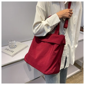 Detailed view of a red large-capacity corduroy tote bag worn as a shoulder bag