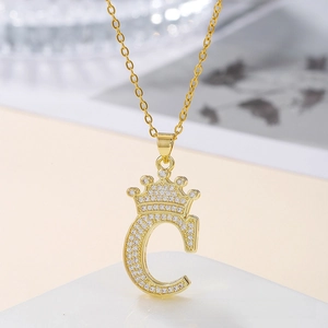 Macro detail of gold crown letter C pendant with sparkling pavé zircons on chain