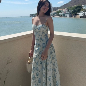 Détail d'une robe d'été à fines bretelles avec fleurs bleues sur fond blanc